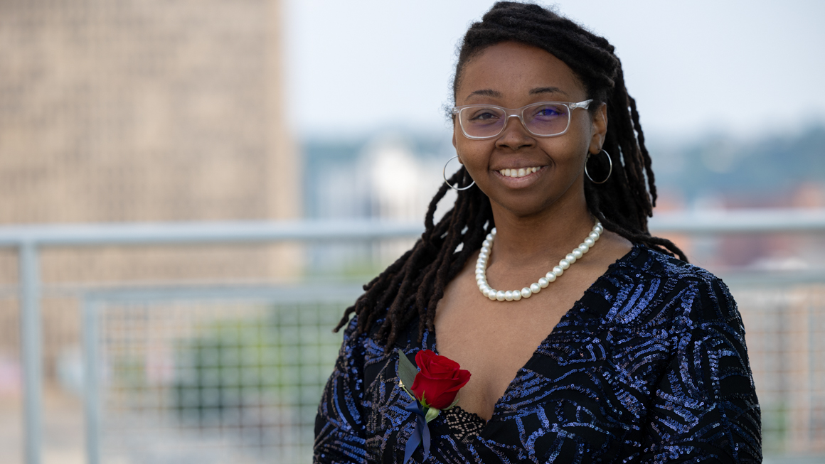 Ph.D. Counselor Education and Supervision alum Dr. Kenya Johns as Mayor of Beaver Falls outside of school building smiling and wearing a rose