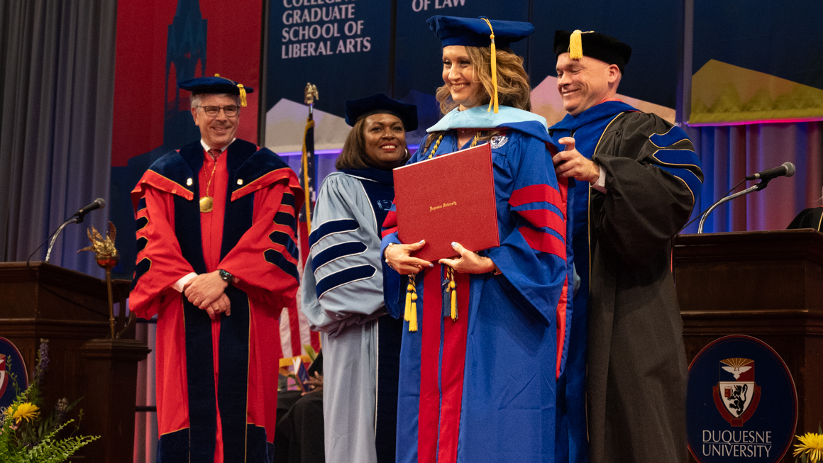 Dr. Odeese M. Ghassa-Khalil being hooded for her doctorate degree on the School of Education Commencement stage by faculty and President Gormley