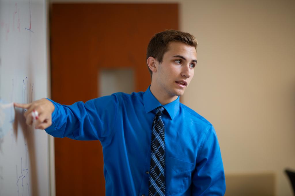 Undergraduate student teaching at board in classroom