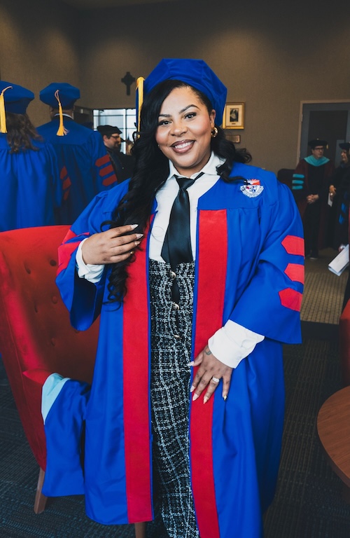 Ed.D. Educational Leadership alumna and awardee De’Jour Young in cap and Gown in campus building on commencement day.
