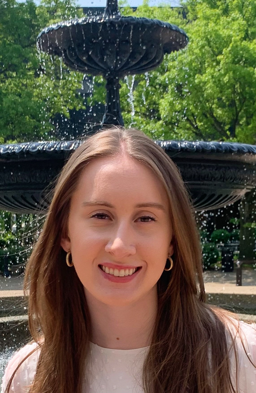 M.S.Ed. ABA student Katelyn Niggemyer outside on campus with trees and water ountain in background