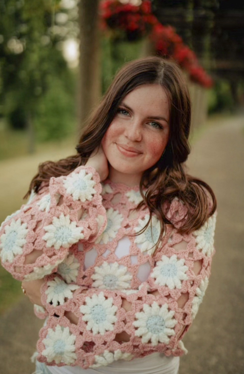 School of Education Educators of Impact scholarship student B.S.Ed. Dual Certification Early Childhood Education and Special Education, K-12 undergraduate Lizzie Washine smiling with backdrop of road lined by trees and flowers in a diagonal behind her.