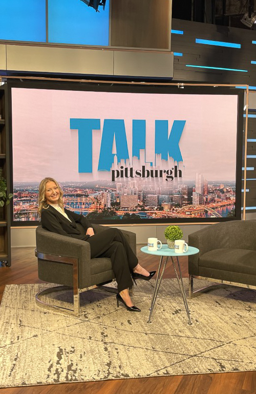 Photo of Maggie Burke at KDKA studios on set of Pittsburgh Talk with the show signage behind her