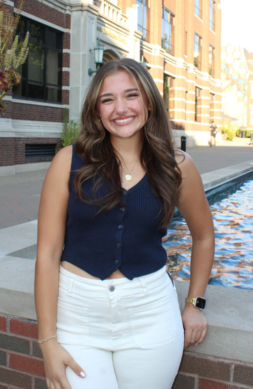 B.S.Ed. Early Childhood Education student Tally Cicione smiling and leaning on Canevin Hall water fountain outside on sunny day.
