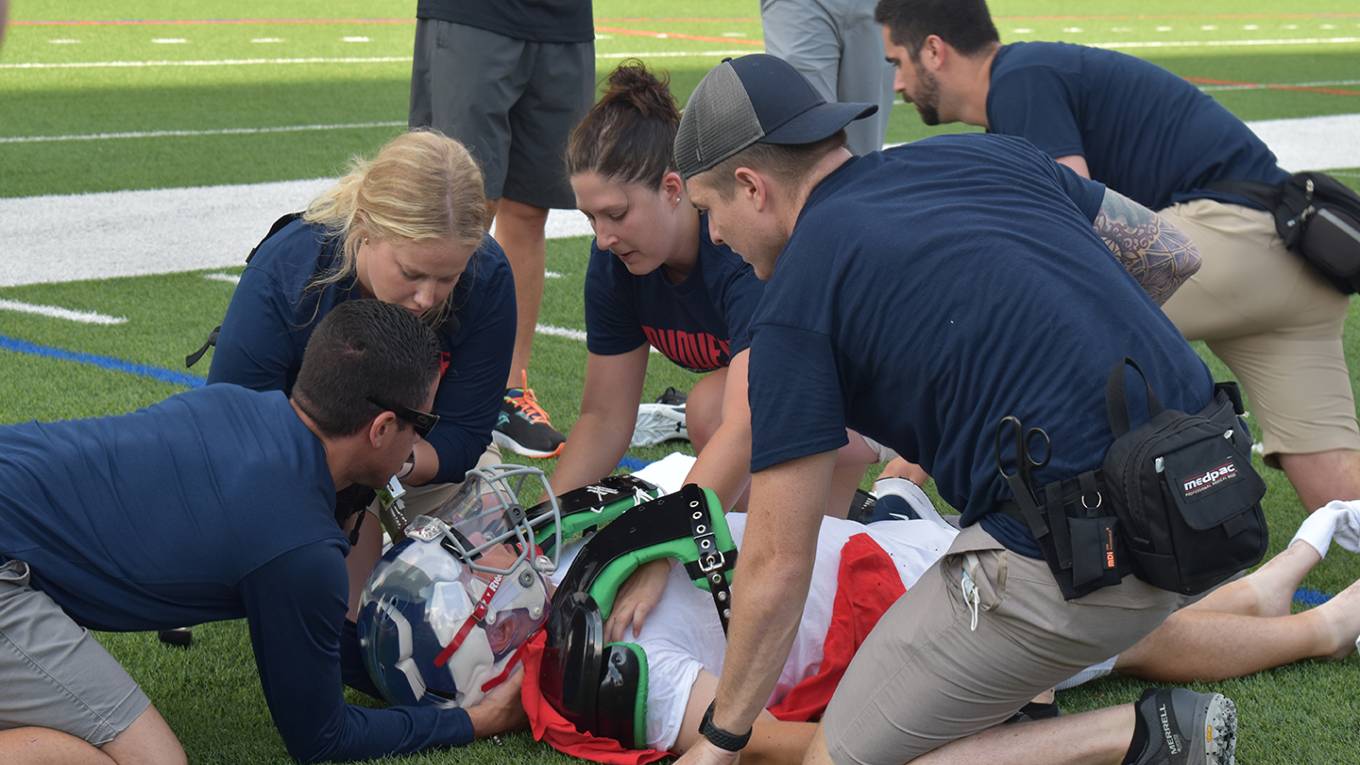 Trainers helping football player.