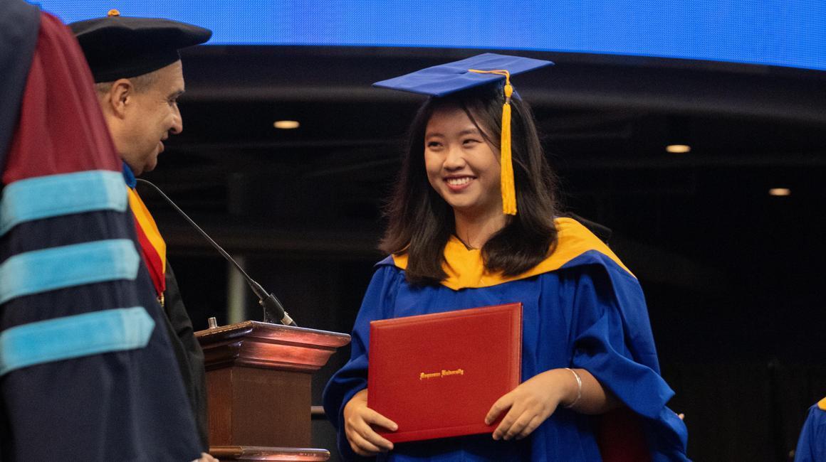 The Dean smiles at Student graduate