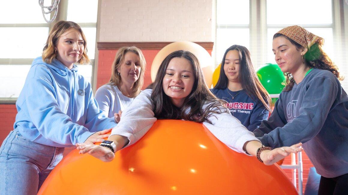 Dr. Retta Martin and OT students practice a ball balancing exercise in class.