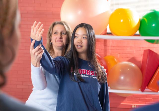 Faculty member demonstrating range of motion exercises on an OT student.