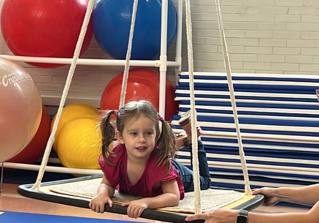 OT Student helping a small child use a platform swing.