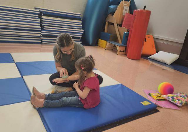 OT student practicing brushing therapy on a small child.