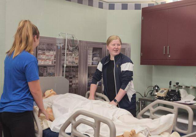 Two occupational therapy students practicing their skills in the OT lab. 