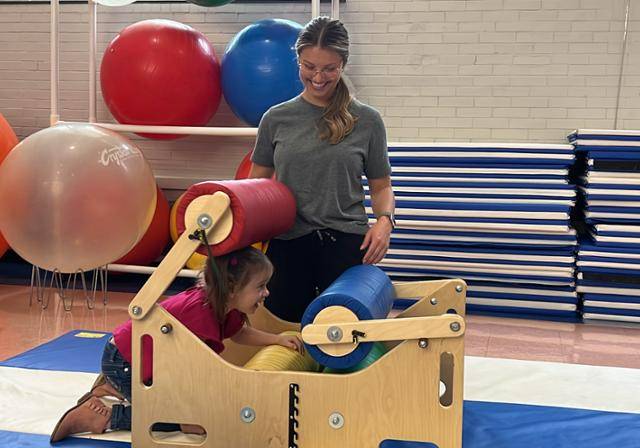 An OT student guiding a little adventurer through a sensory jungle in the peds lab.