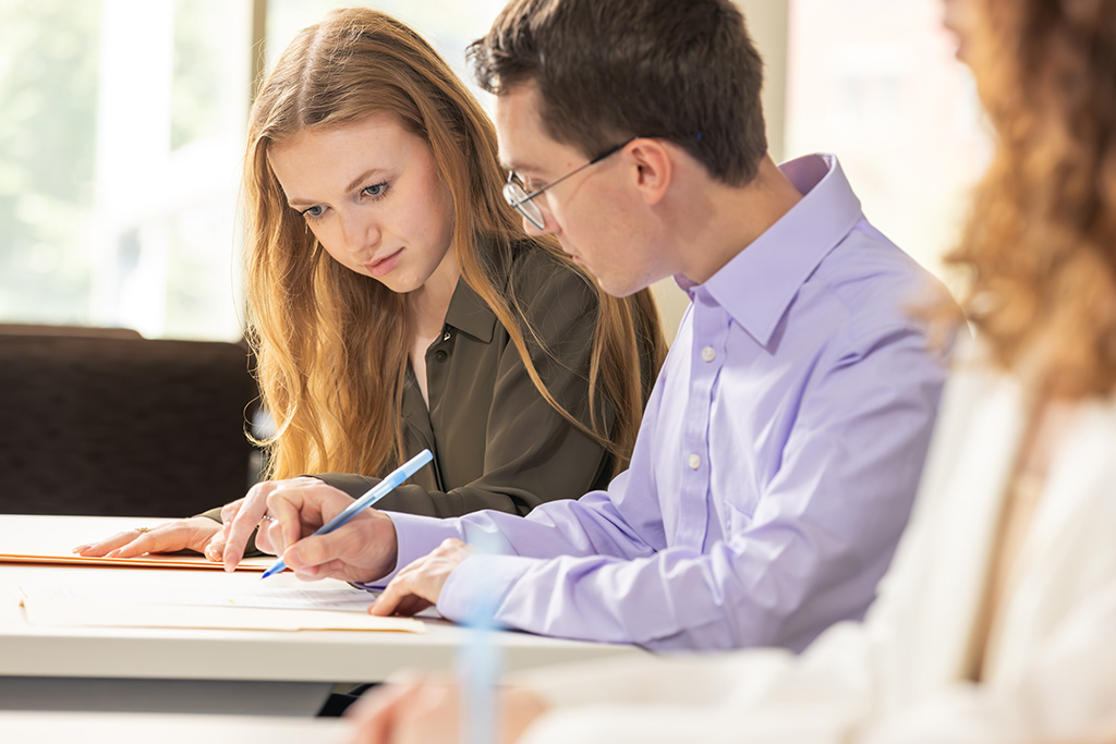 Female and male law student reviewing a textbook together