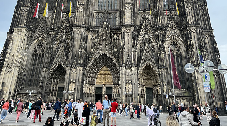 Outside of European cathedral with people in foreground entering, observing, exiting