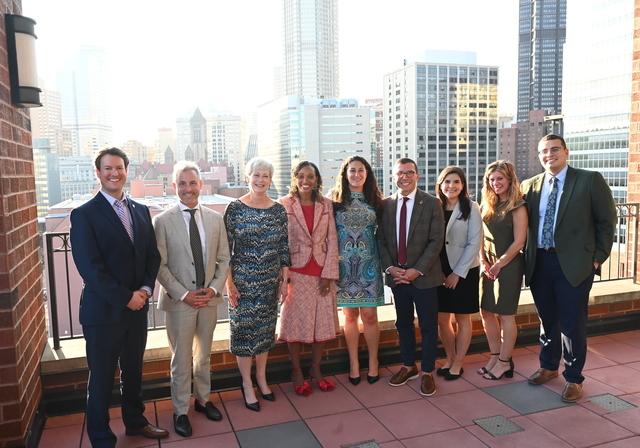 A group of Duquesne Kline Law Alumni Association Board members standing on a balcony with a view of the city of Pittsburgh in the background. 