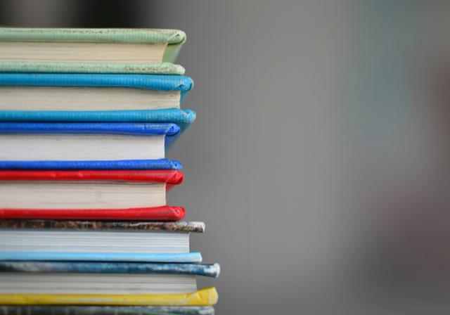 A stack of school books with brightly colored bookcovers.