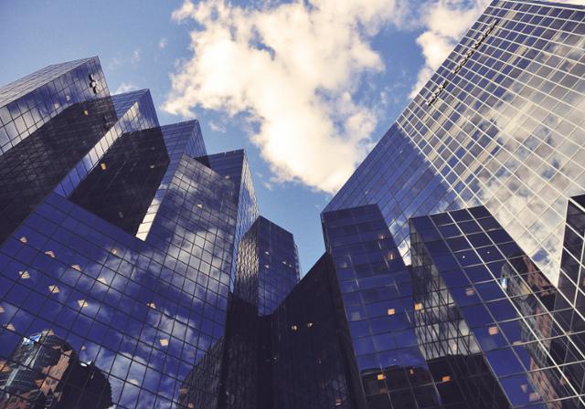 Skyscrapers against a blue sky.  The glass of the skyscrapers reflects the sky and other surroundings.