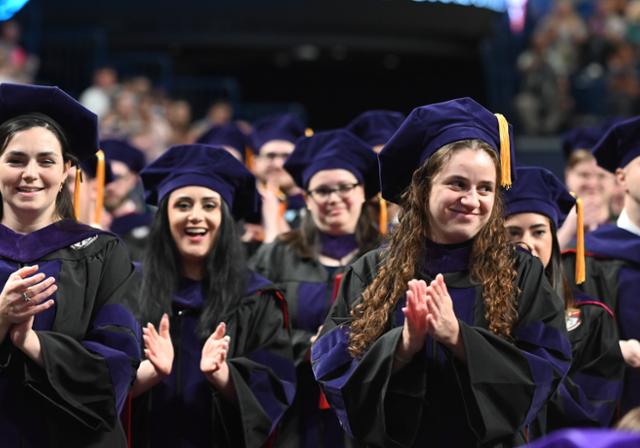 Group of female graduates clapping at commencement