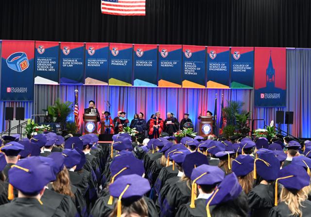 Graduates in caps at commencement ceremony looking at stage.