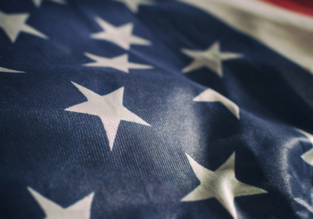 Folded United States flag with white stars on blue fabric featured prominently in the photo.