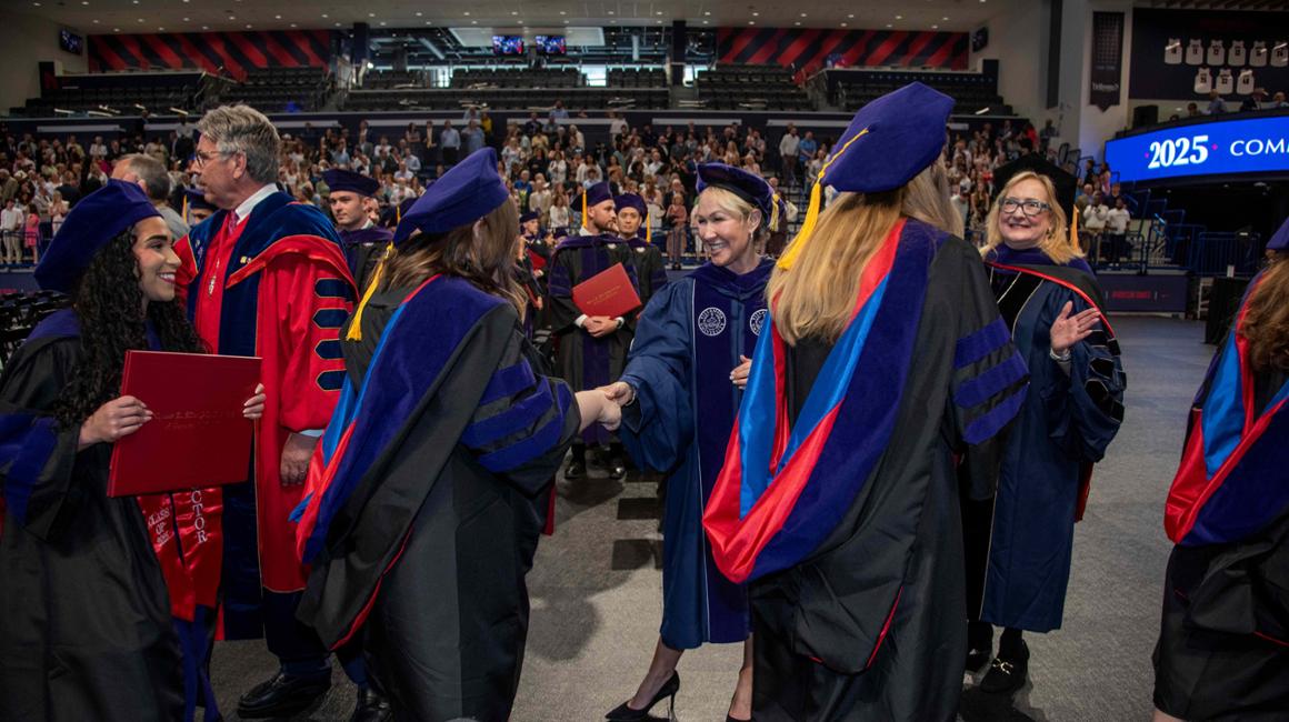 Graduates and president and dean high fiving