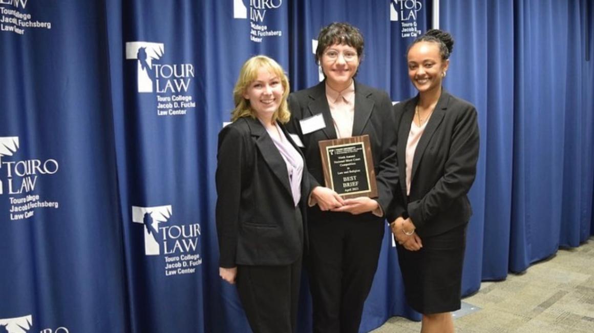 Three students holding award