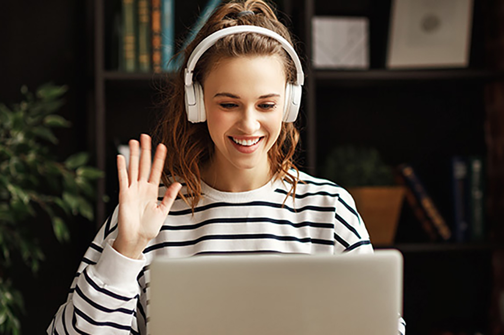 Student on laptop waving at online class