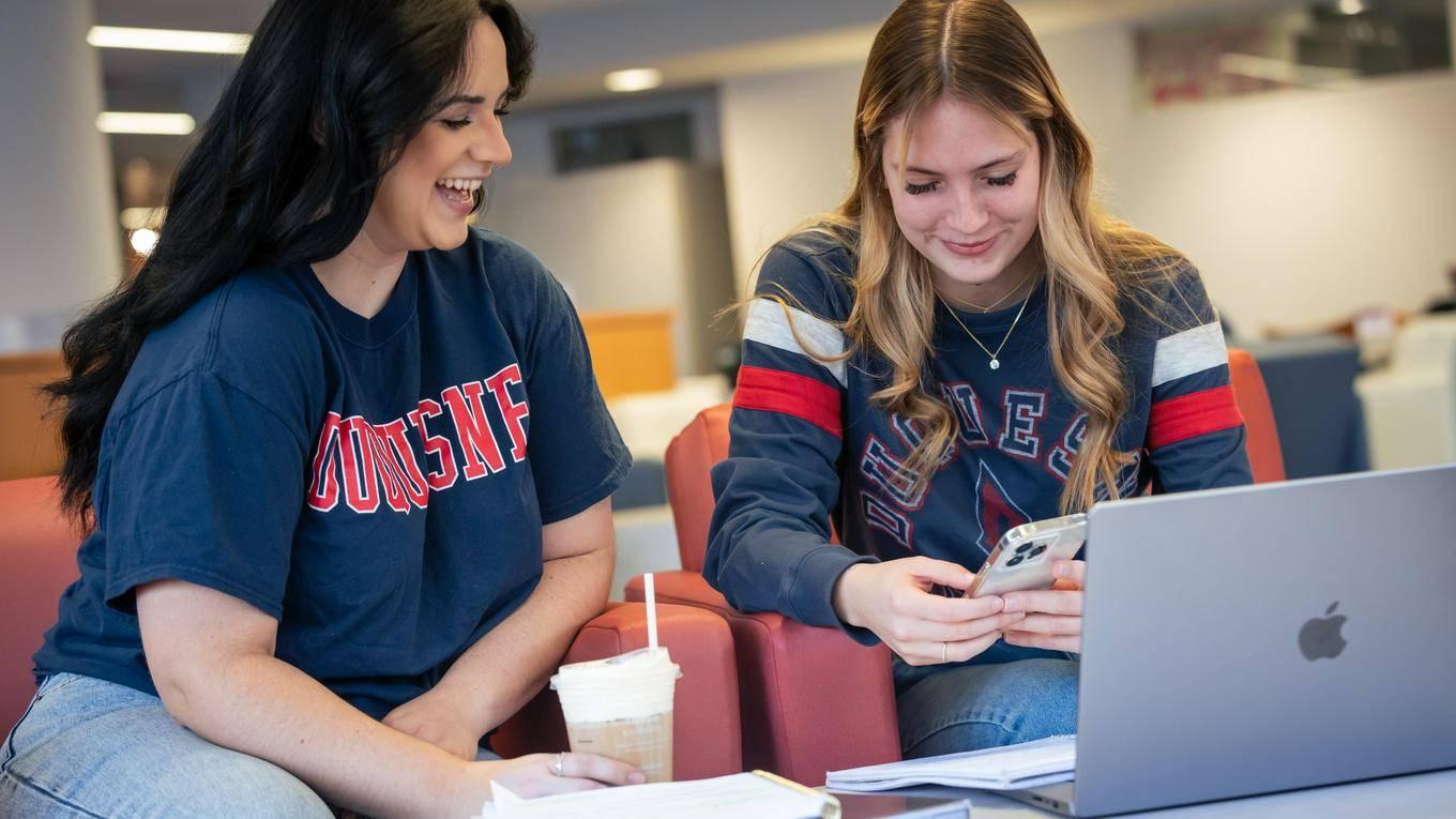 Two students looking at a graphic on a cell phone 