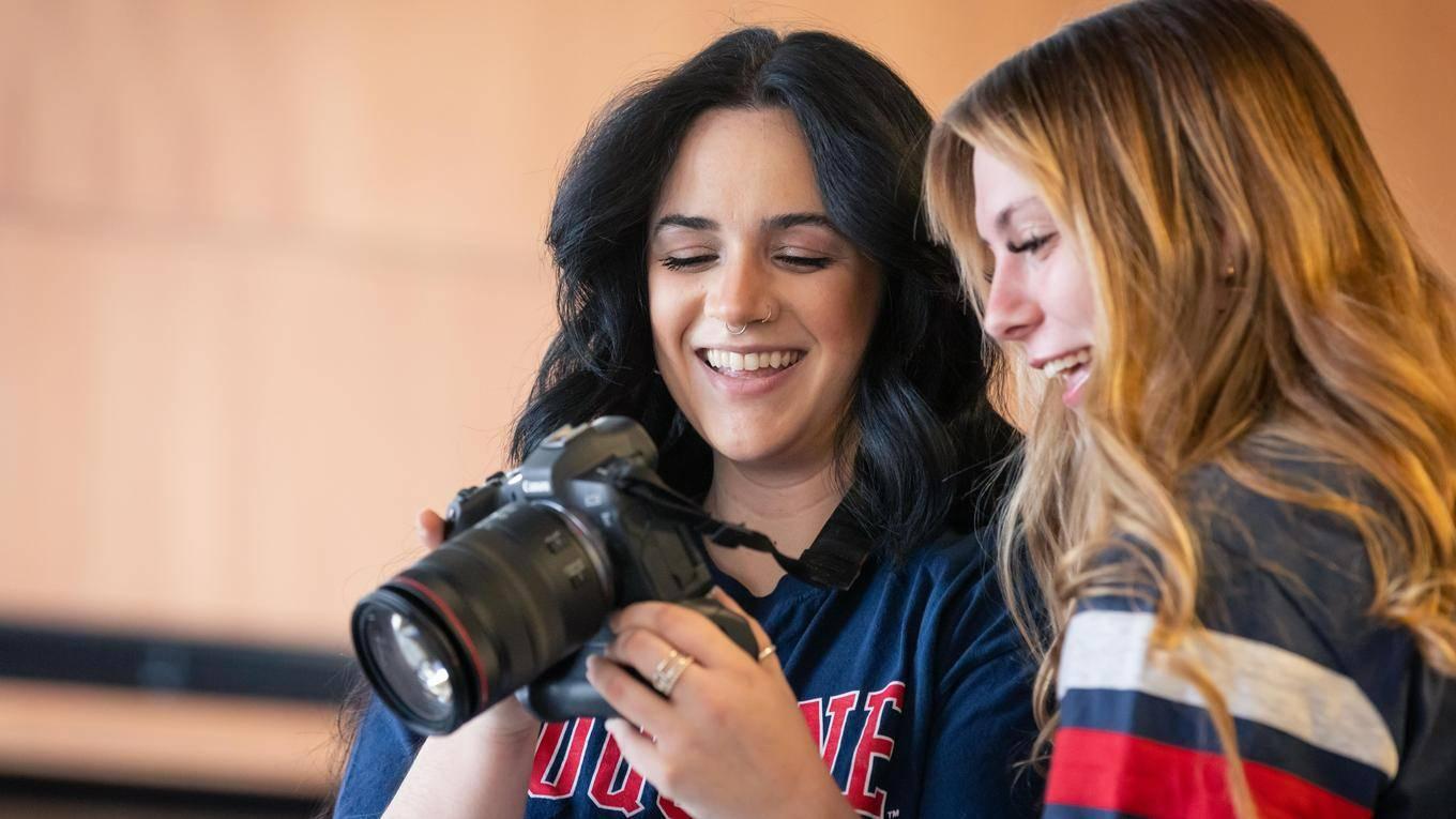 Two students looking at the screen of a camera after a photo was taken