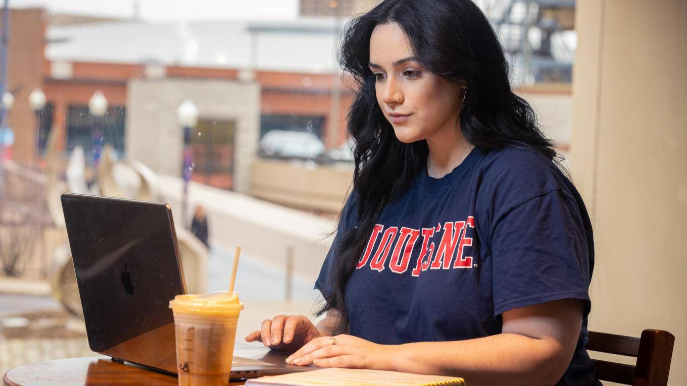 Student working on her laptop in a coffee shop