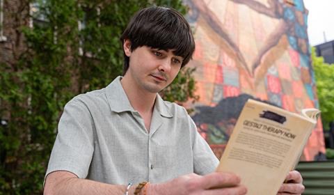 Aidan Reilly reads a book in the community garden on Academic Walk.