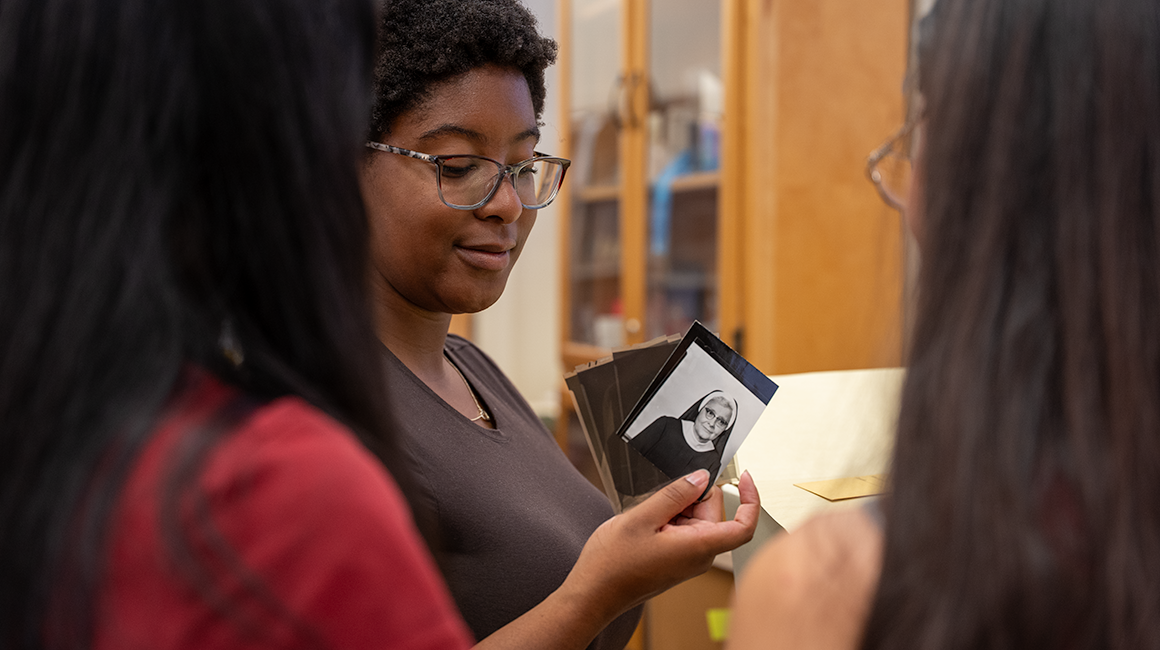 Three students inspect photos in archives.