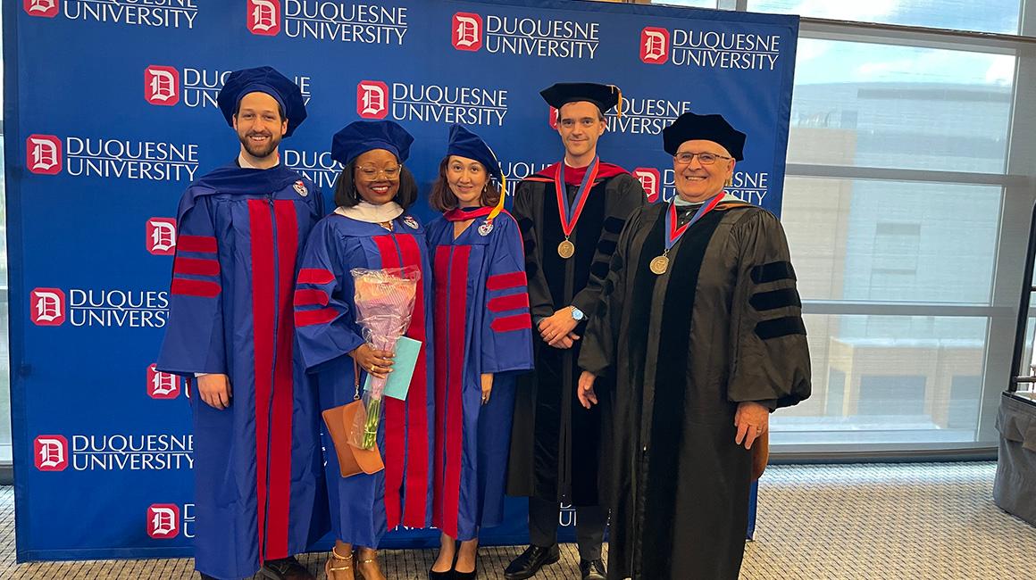 Students and faculty in graduation gowns posing for a picture.