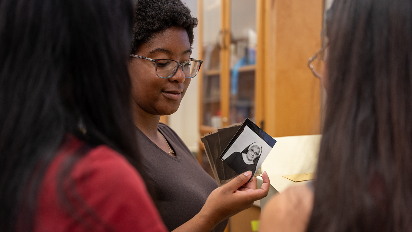Three students examine negatives of pictures in the UPMC Mercy Archives.