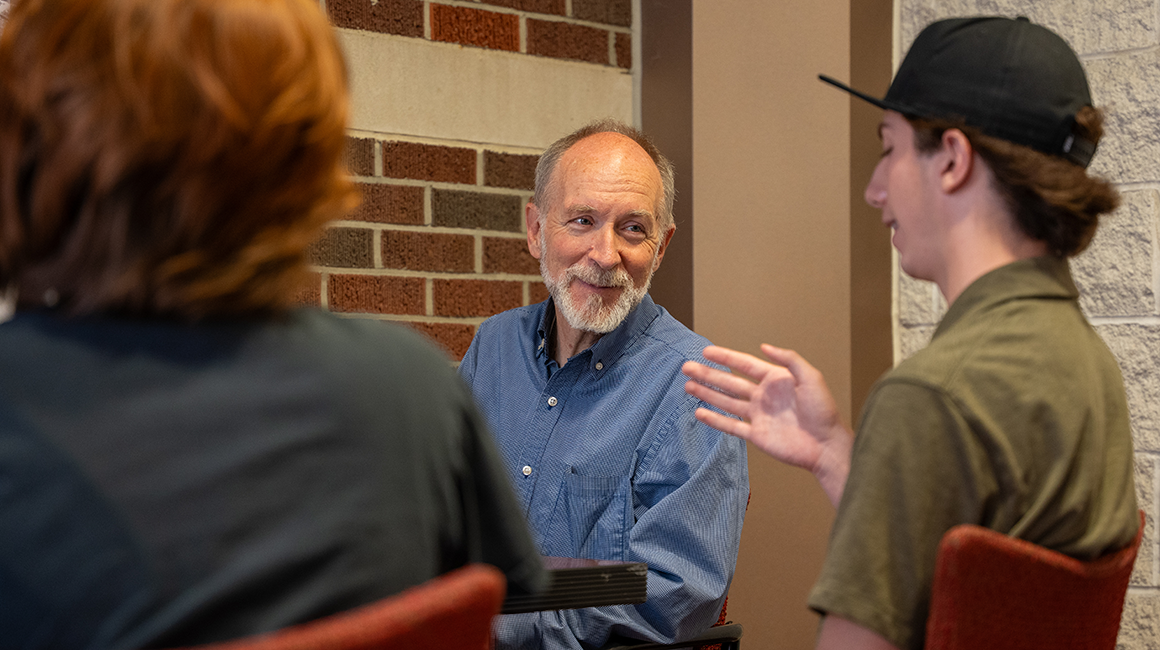 Dr. James Swindal speaking with two philosophy students.