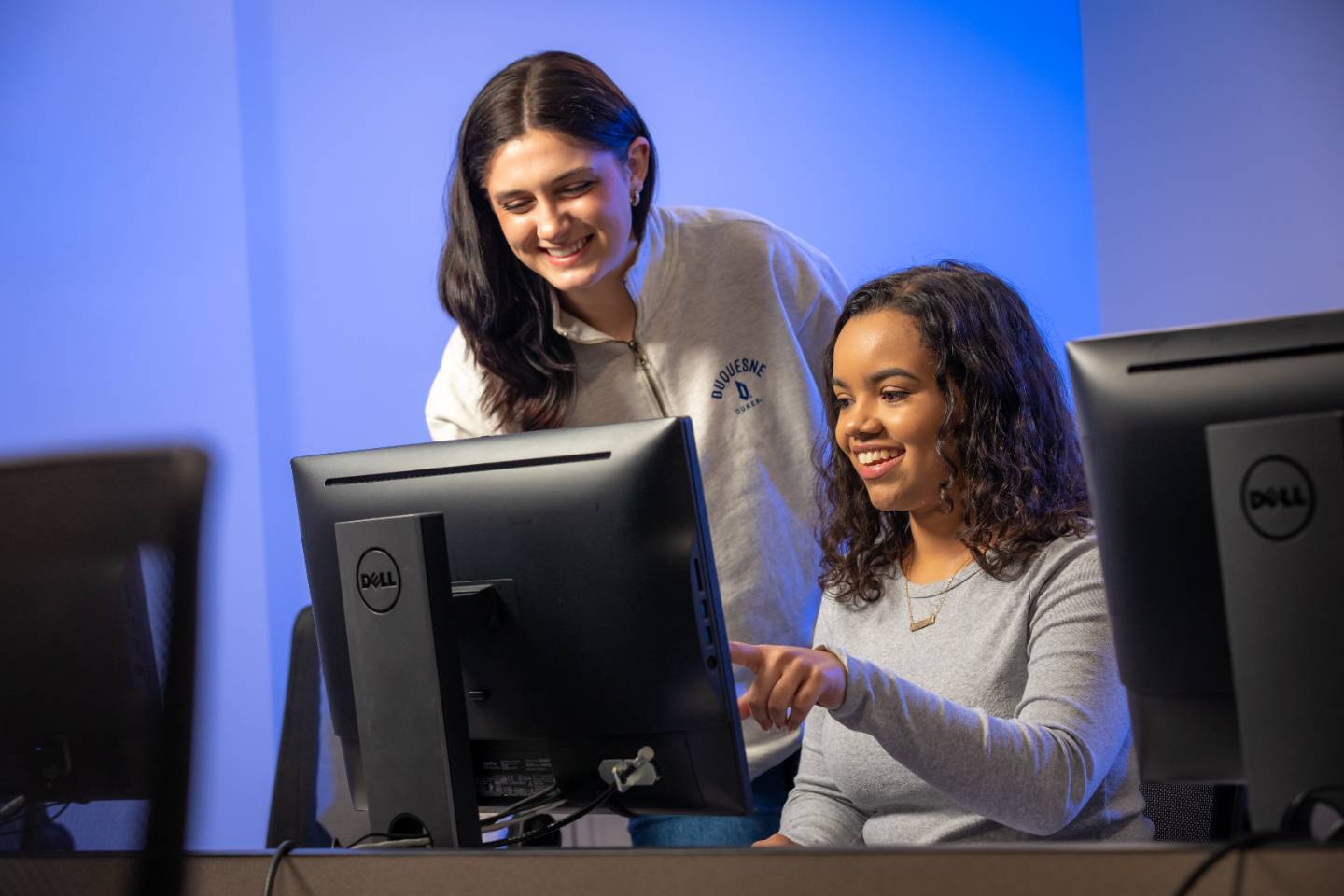 Two female students collaborating on a computer in the computer lab