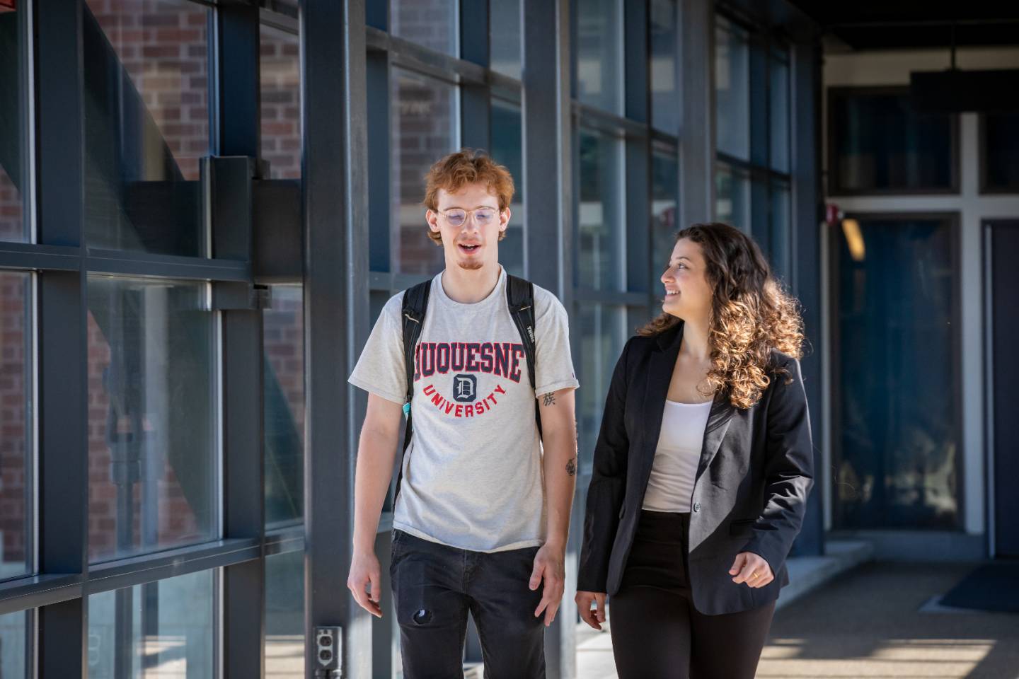 Two students walking over skywalk on campus