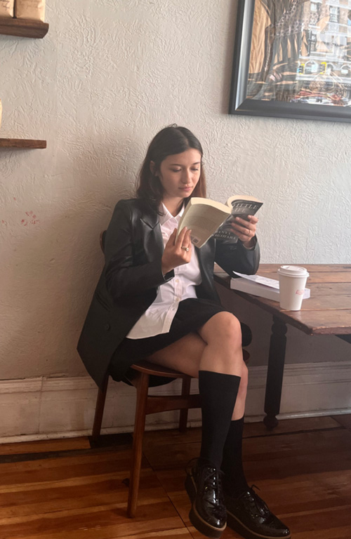 Female student sitting in a coffee shop reading a book.