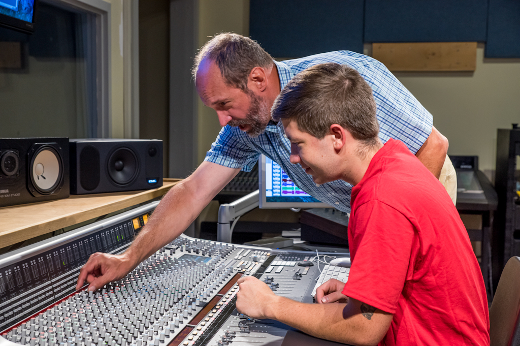 Faculty member instructs student at a mixing console.
