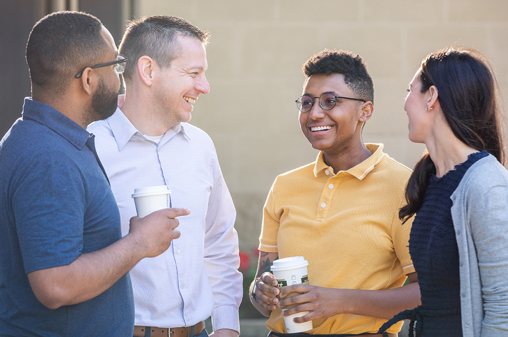 Four people talking and drinking coffee.