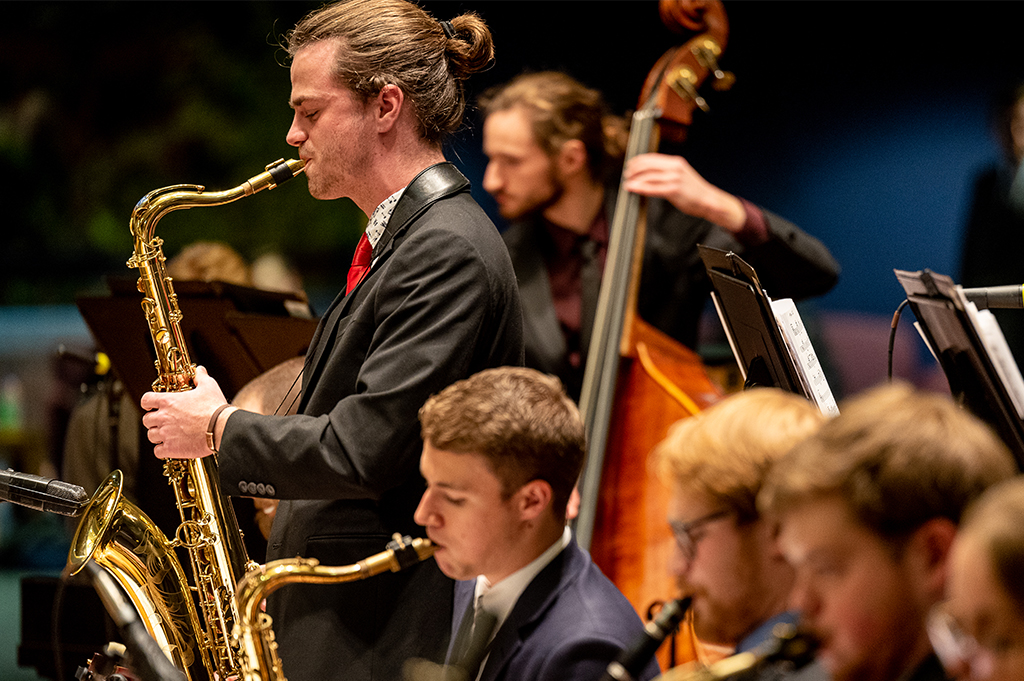 A saxophonist stands and solos at a jazz ensemble concert.