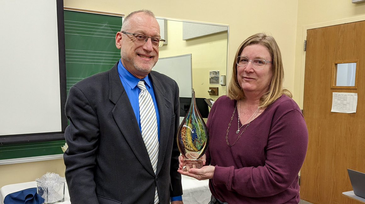 Dean David Allen Wehr poses with retiring faculty member Elaine Abbott, who holds an award presented to her for her dedicated service.