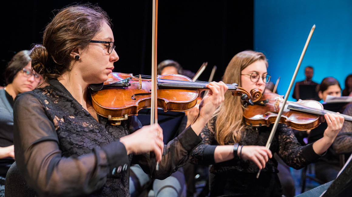 Students perform on string instruments.