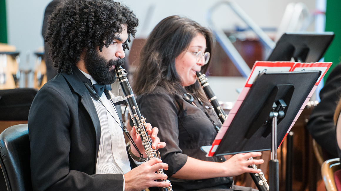 Students play clarinets in a performance.