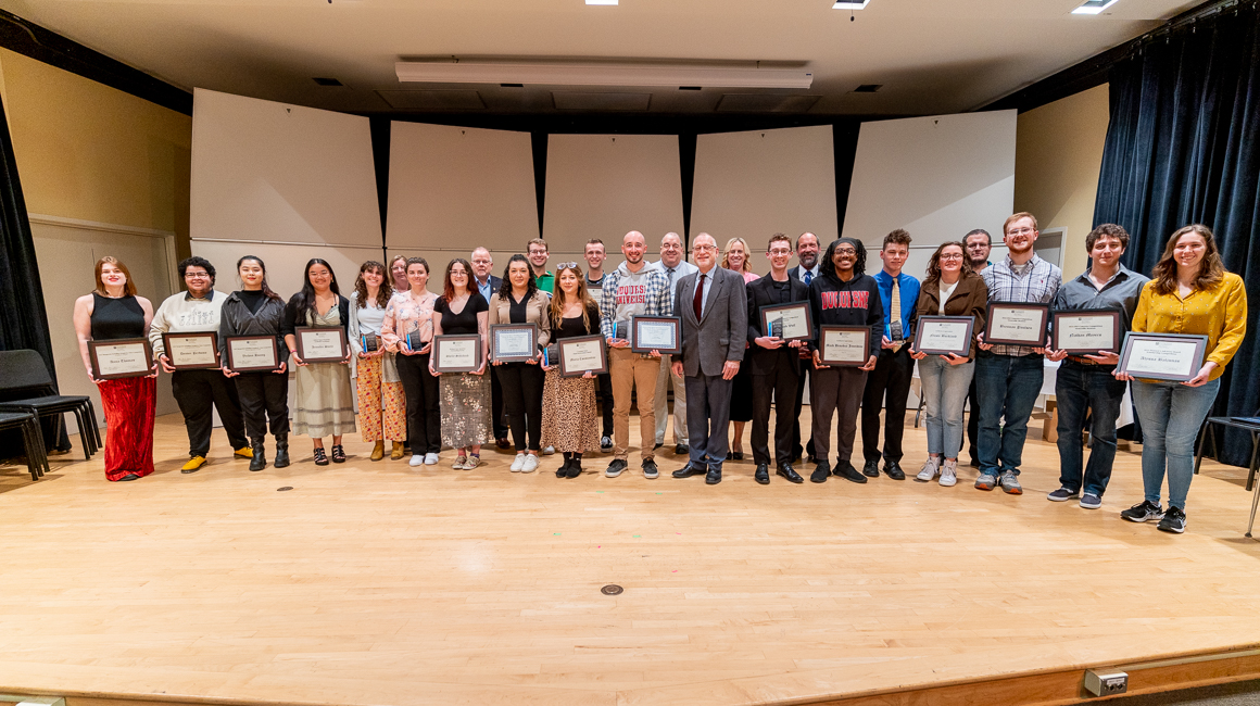 Award winners pose with presenters on stage.
