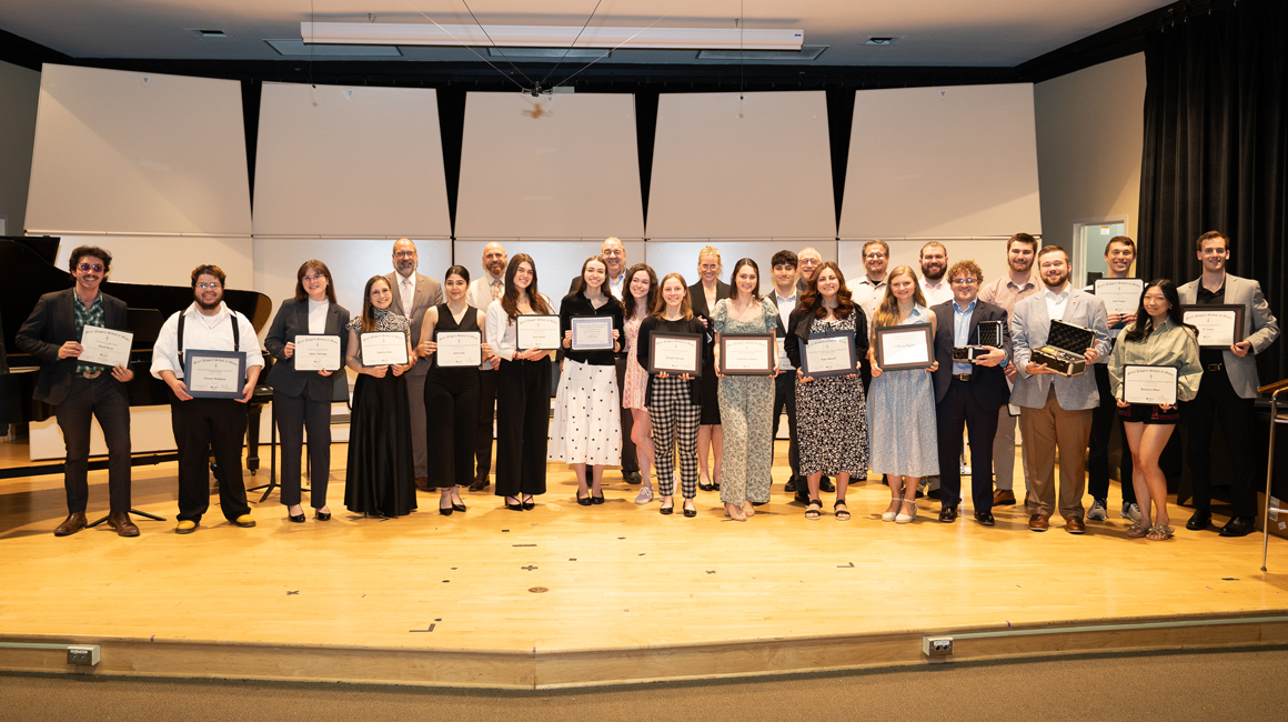 Students and faculty hold awards on the stage of PNC Recital Hall.