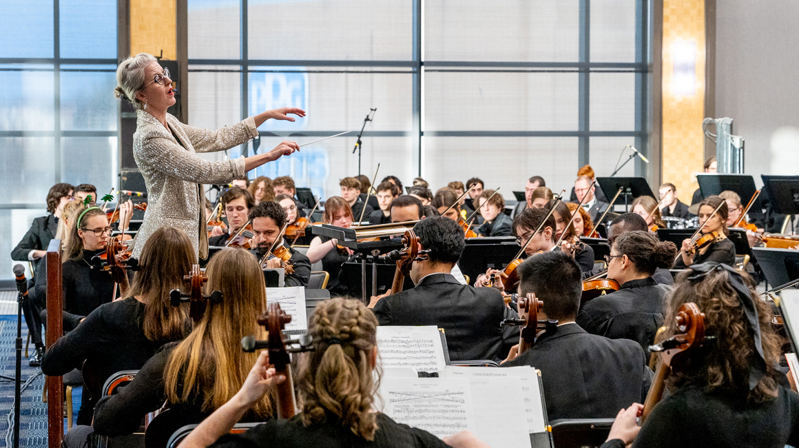 A conductor leads an ensemble in performance.