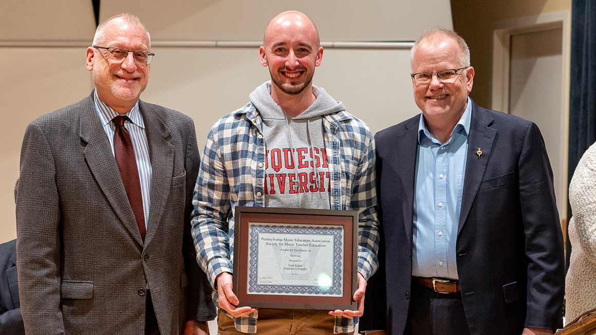 Student poses with their award, alongside Dean and Department Chair for a photo.