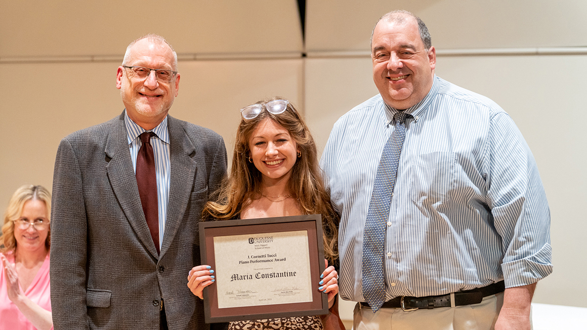 Student poses with their award, alongside Dean and Department Chair for a photo.