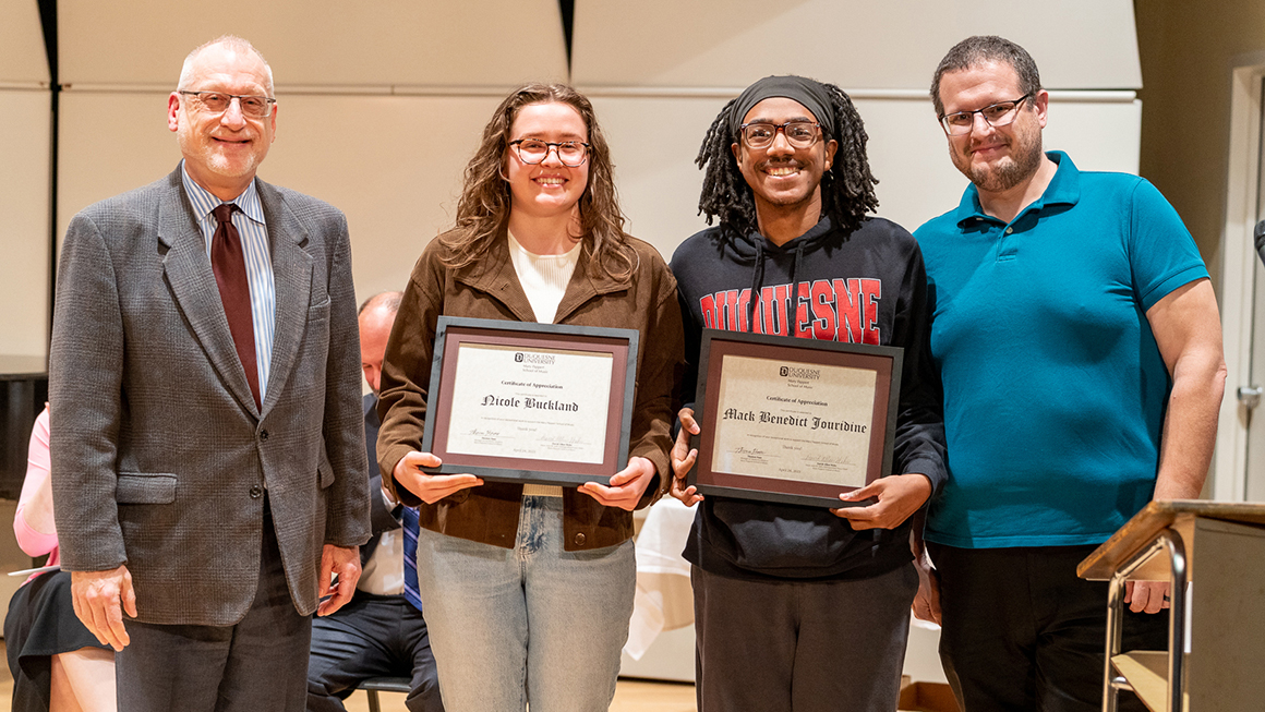 Student poses with their award, alongside Dean and Department Chair for a photo.